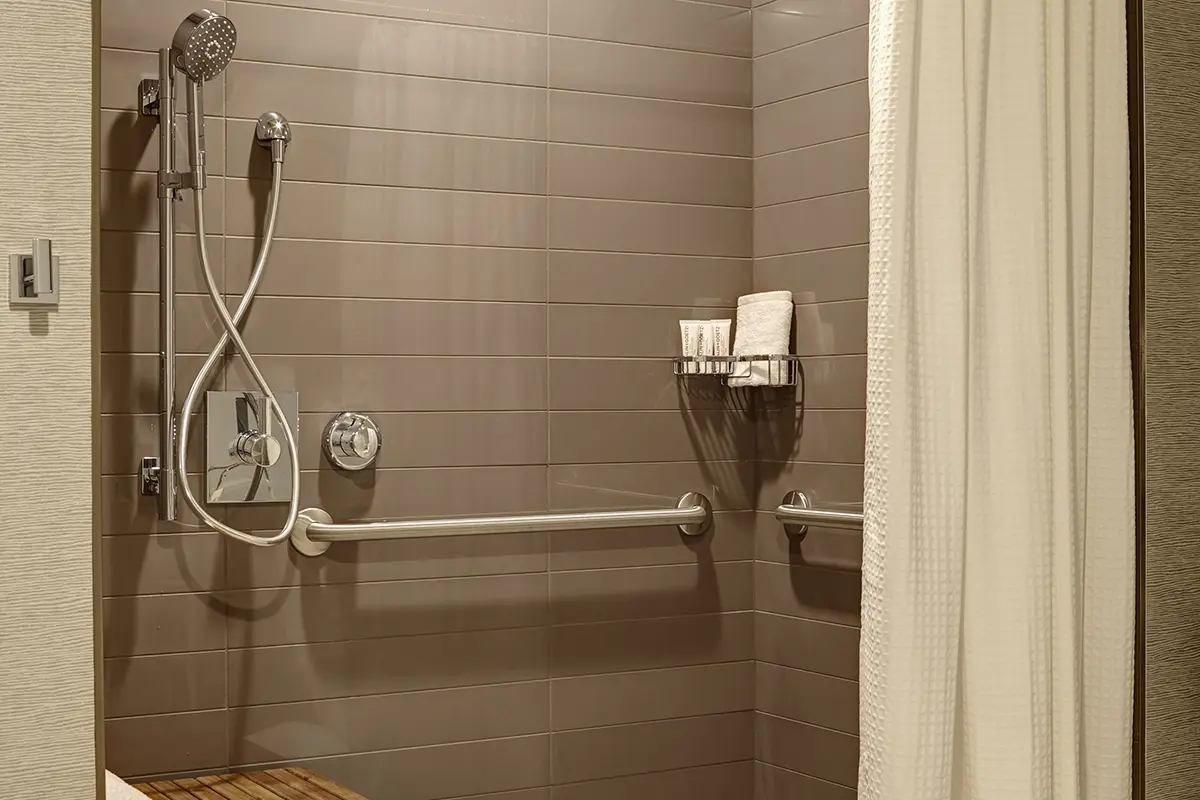 King Suite - mobility-accessible roll-in shower with shower seat and grab bars in bathroom