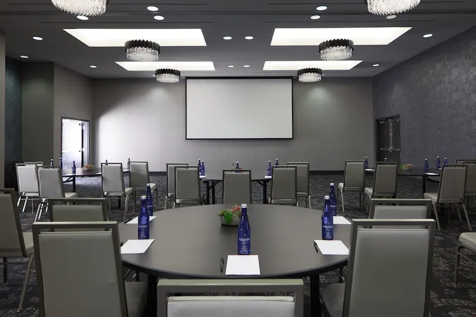 Great Room - corporate event with round tables and high-back chairs facing a projector screen