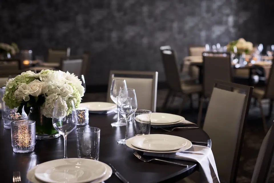 Great Room - banquet table set with glassware, candles and a white floral arrangement