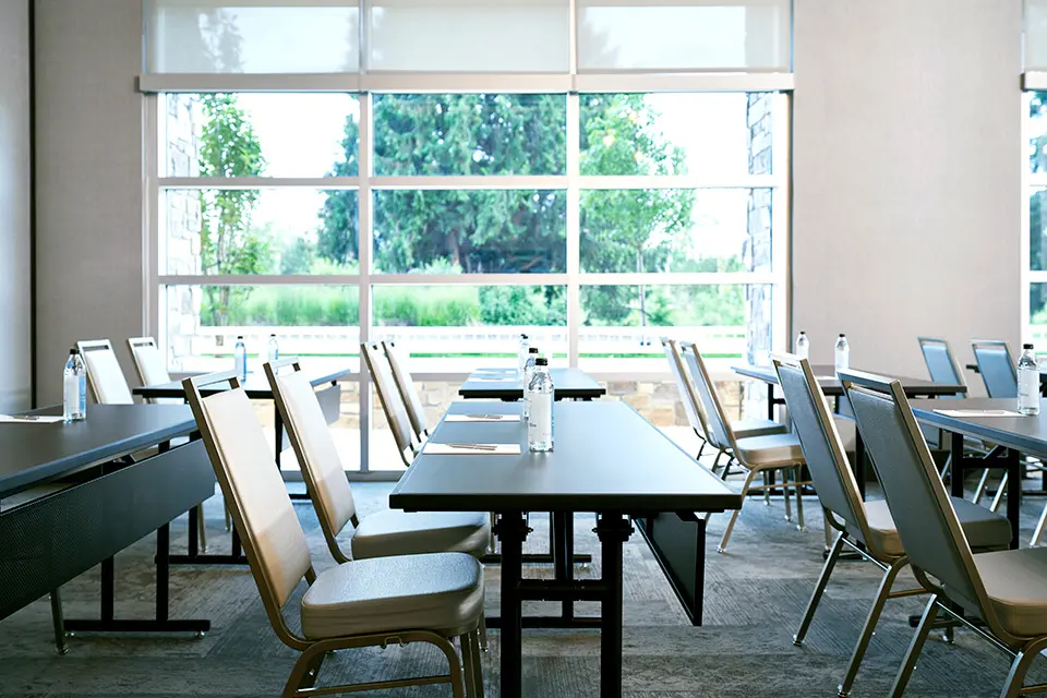 Great Room - corporate classroom setup featuring bottled water, notepads and floor-to-ceiling windows