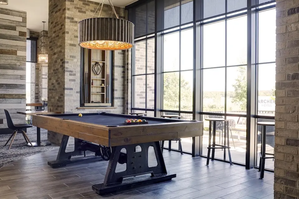 AKB - bar-side billiards table next to large grid windows offering neighborhood views