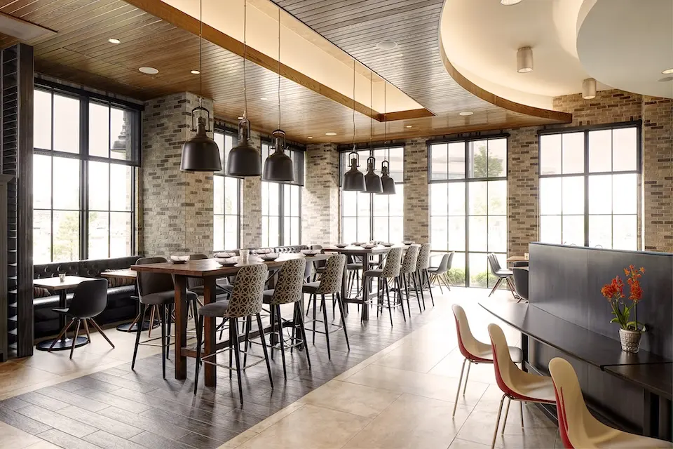 AKB - industrial-styled dining room with high-top communal tables and booth seating