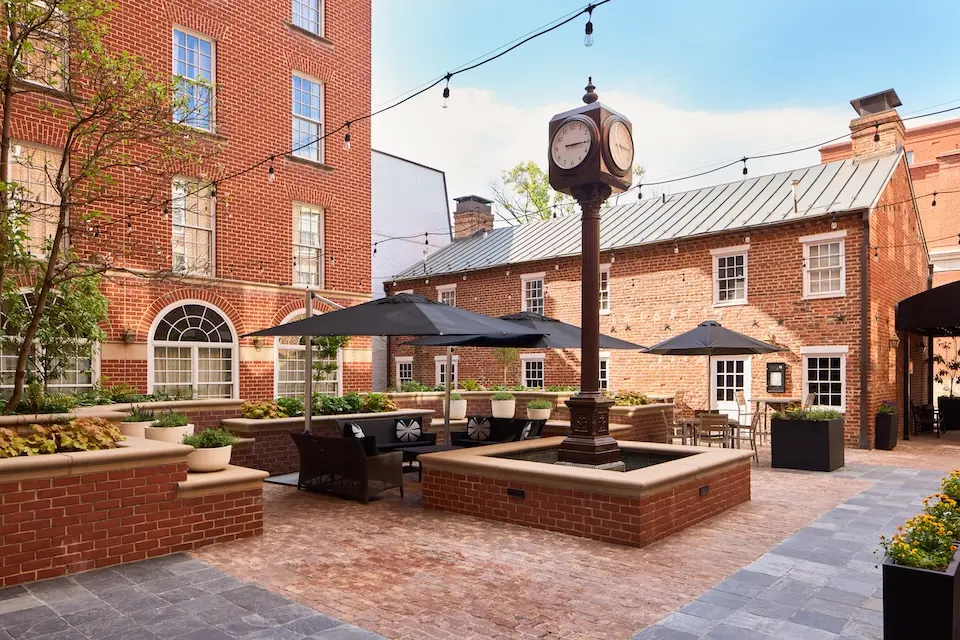 Courtyard - hotel courtyard featuring a historic-style post clock surrounded by brick architecture, patio seating and string lights