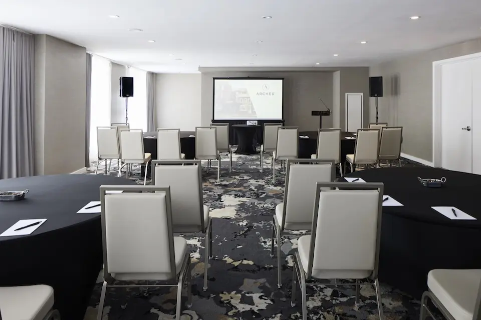 Liberty - corporate event with round tables and high-back chairs facing a projector screen