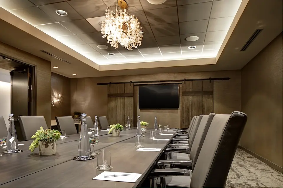 Krug Salon - intimate boardroom with a long conference table, crystal chandelier and wall-mounted TV
