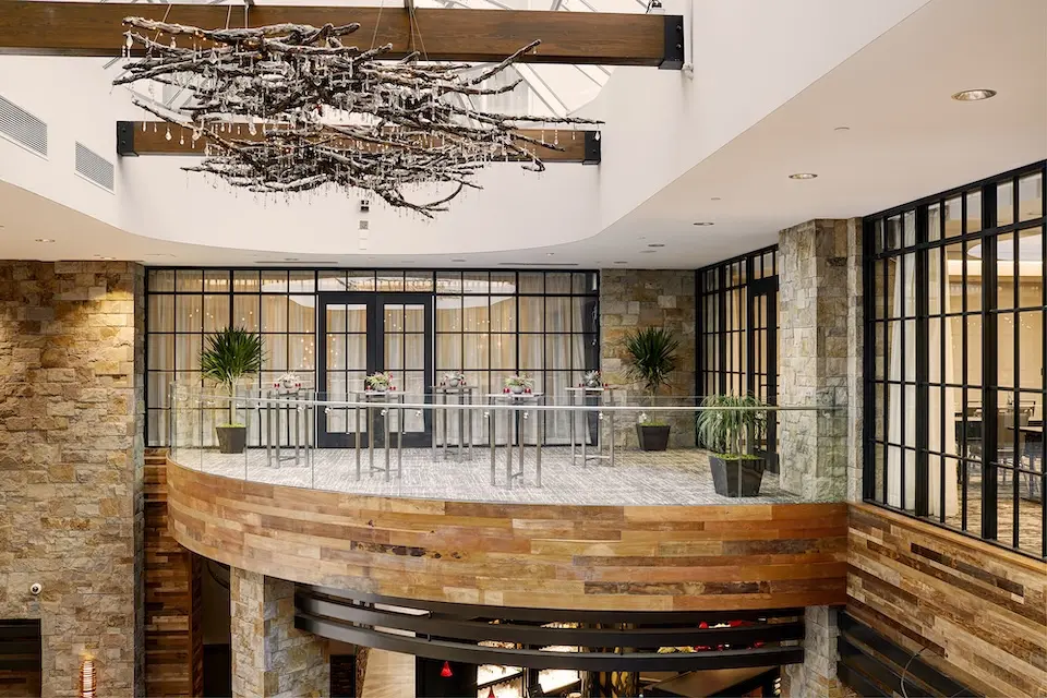 Balcony - atrium with stone walls and glass railings, set with cocktail tables