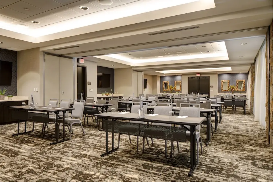 Great Room - corporate event featuring a classroom setup with narrow tables, high-back chairs, bottled water and notepads