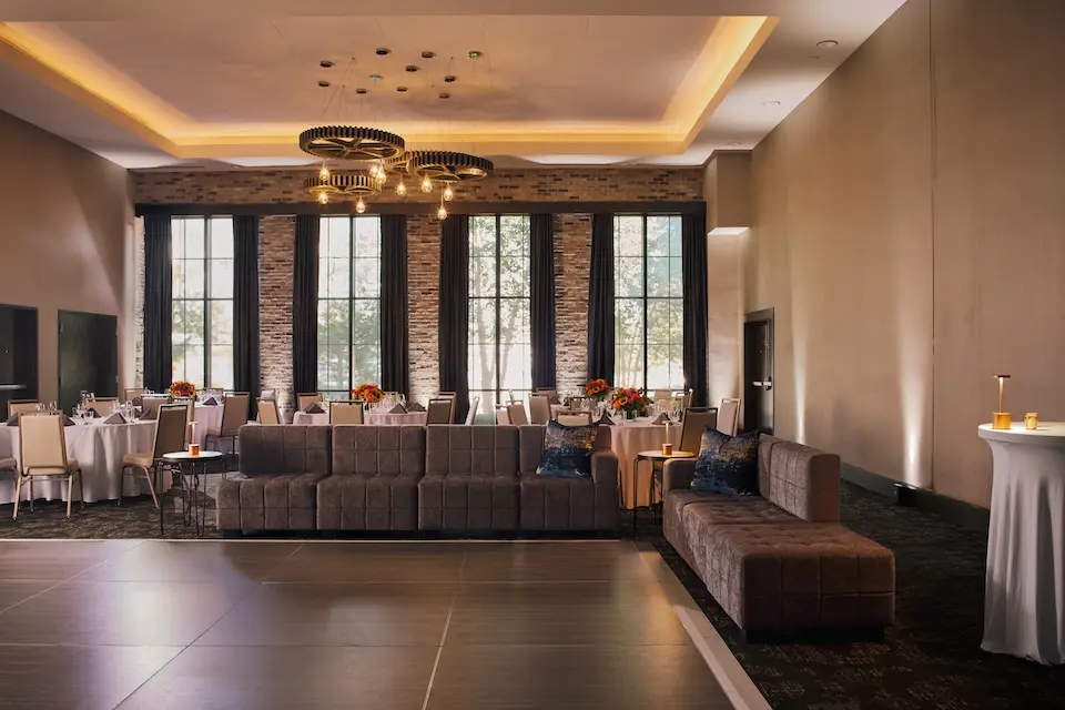 Great Room - social event featuring a wooden dance floor surrounded by grey sectional sofas and banquet tables