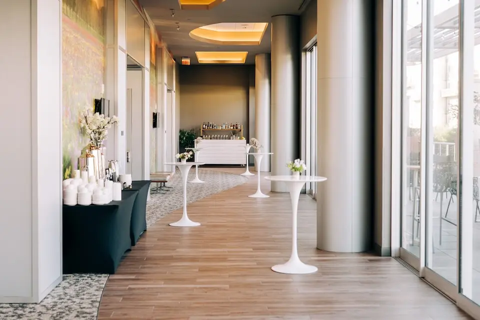 Grand Salon Foyer - prefunction space set with white cocktail tables, a black-draped coffee station and a mobile bar