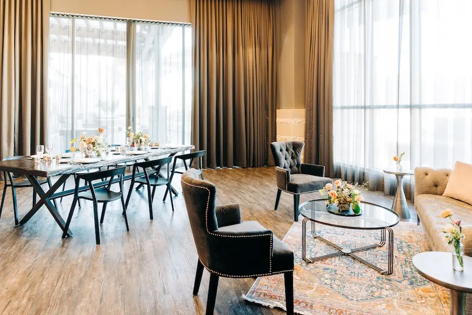 Terrace Suite - window-clad venue featuring a dining table set with glassware alongside a cozy corner seating area