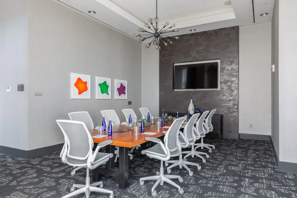 Boardroom - reclaimed wood table with ergonomic white mesh office chairs and a wall-mounted TV