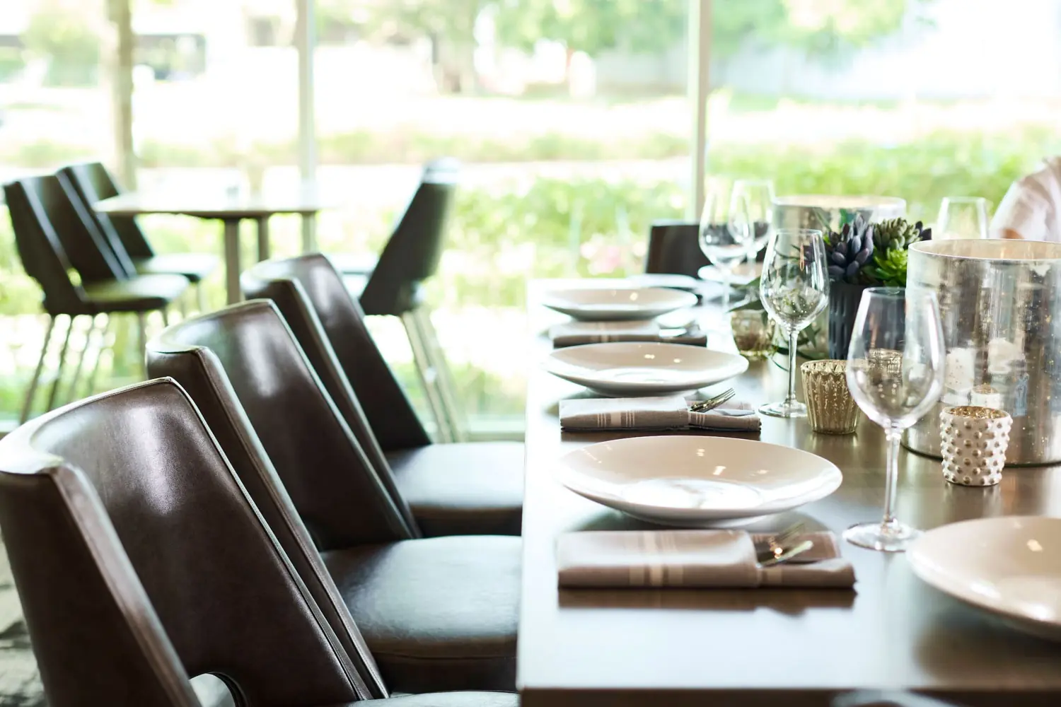 AKB - a modern restaurant dining room table set for dinner, featuring scenic outdoor views through large windows
