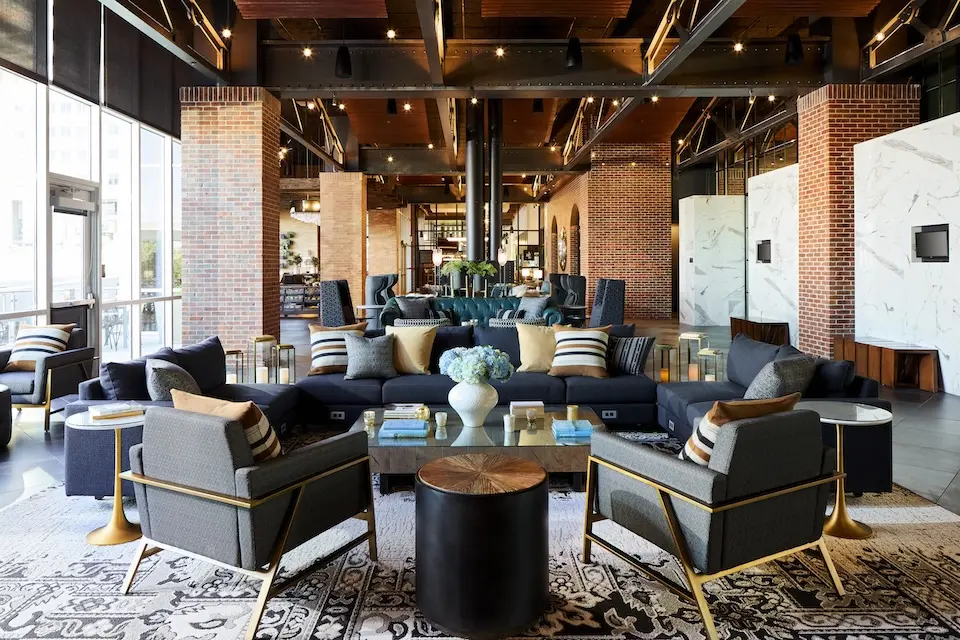 Living Room - semiprivate industrial-chic lounge with dark gray sofas, armchairs and floor-to-ceiling windows