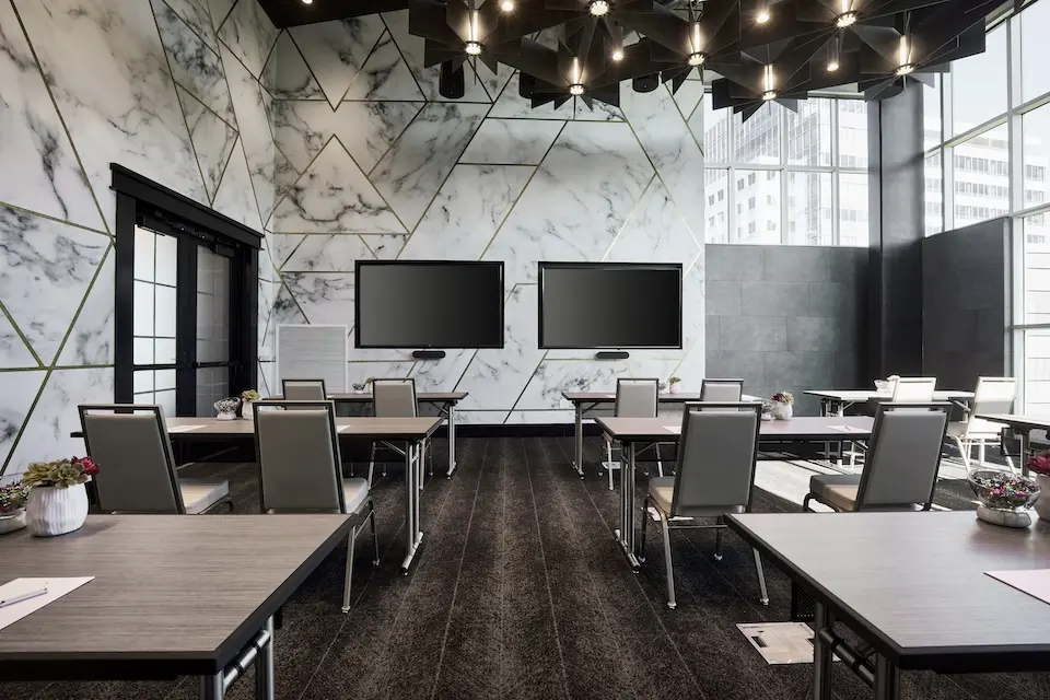 Oasis Salon - a classroom-style meeting setup featuring two wall-mounted TVs against a geometric marble-inspired wallcovering