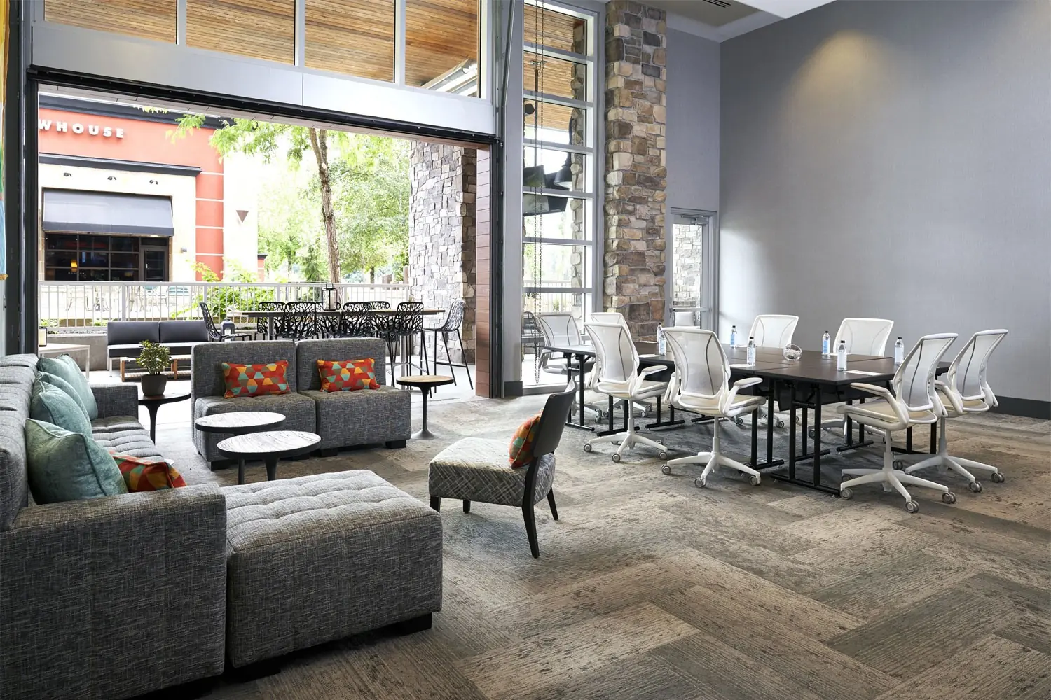 Hospitality Lounge - conference table with movable soft seating and open garage door granting patio access