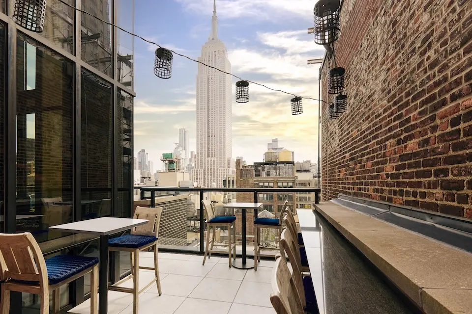 Spyglass - semiprivate open-air terrace with table seating and hanging lantern lights overlooking the Empire State Building
