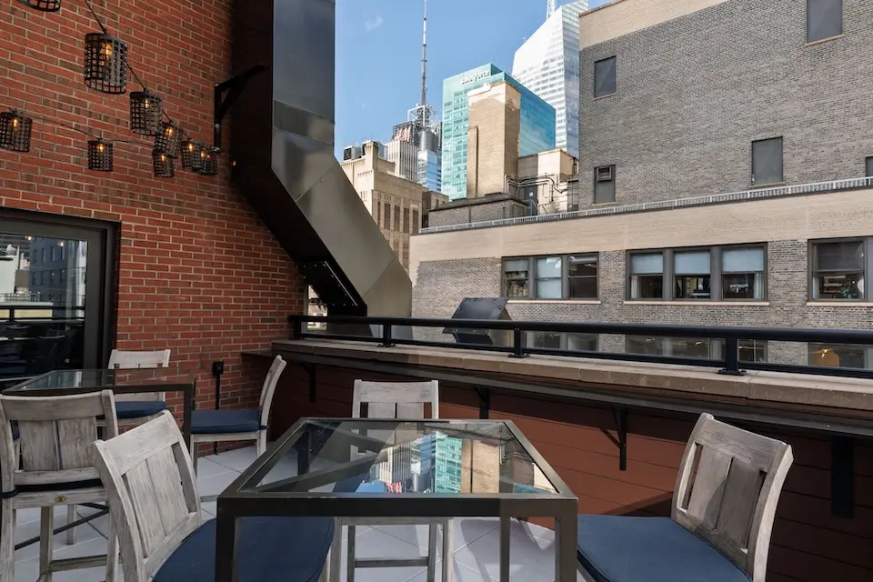 Spyglass - open-air terrace with table seating, hanging lantern lights and Midtown Manhattan views