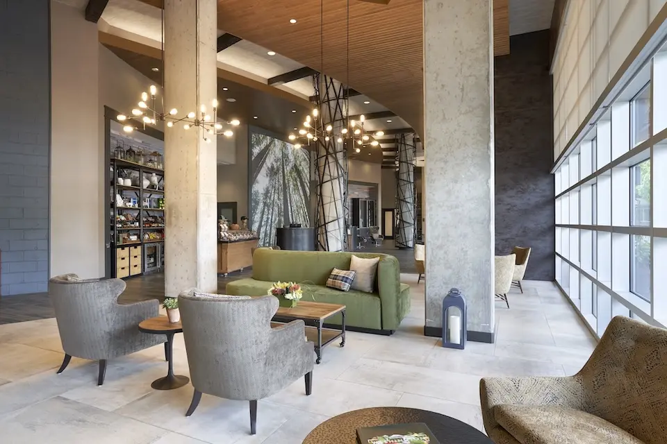 Lobby - spacious boutique hotel sitting area with a green sofa, gray armchairs and decorative branch-like chandeliers