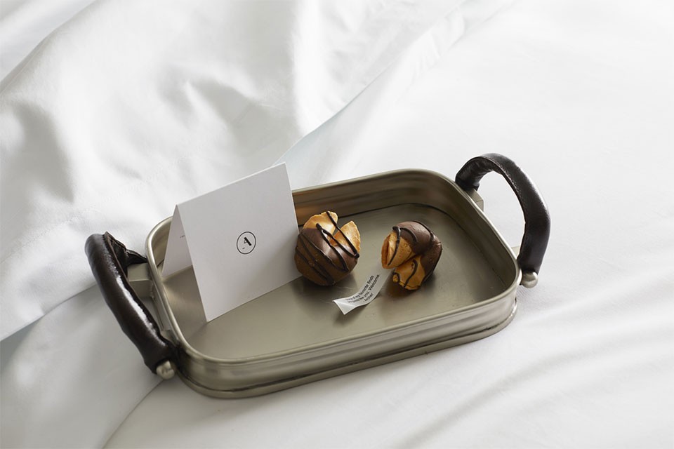 Turndown treat on bed - fortune cookies on a tray with a card