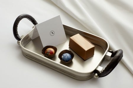 Turndown treat on bed - CIA Chocolates on metal tray with a card