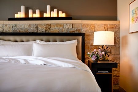 Deluxe King Balcony - a stone wainscot candle-lit wall behind a platform bed and nightstand