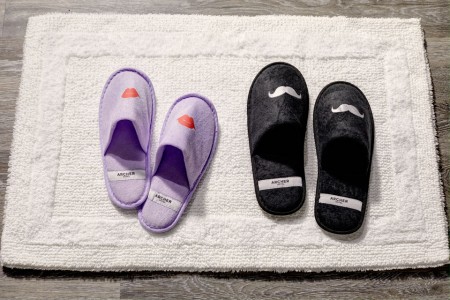 Archer's whimsical slippers with mustaches and lips on bath mat