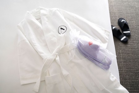 Frette bathrobe on bed with whimsical slippers