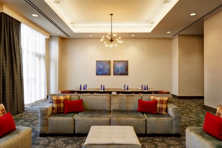 Hospitality Lounge with sofa, chairs and table with chairs in background