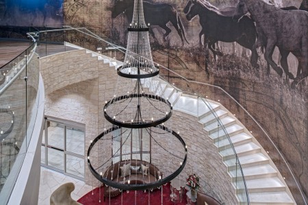 Hotel lobby grand staircase with chandelier and horse wall covering mural