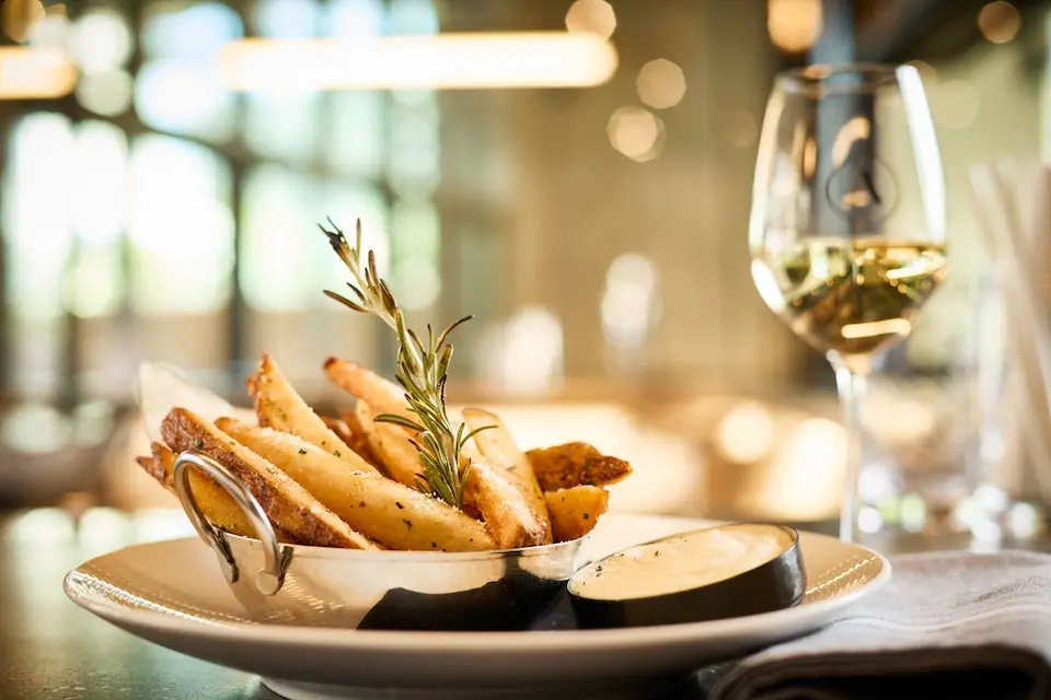 AKB - a plate of shareable rosemary pomme frites with dipping sauce and a glass of white wine