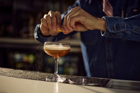 A bartender making a Diamondback cocktail at AKB in Archer Hotel Austin