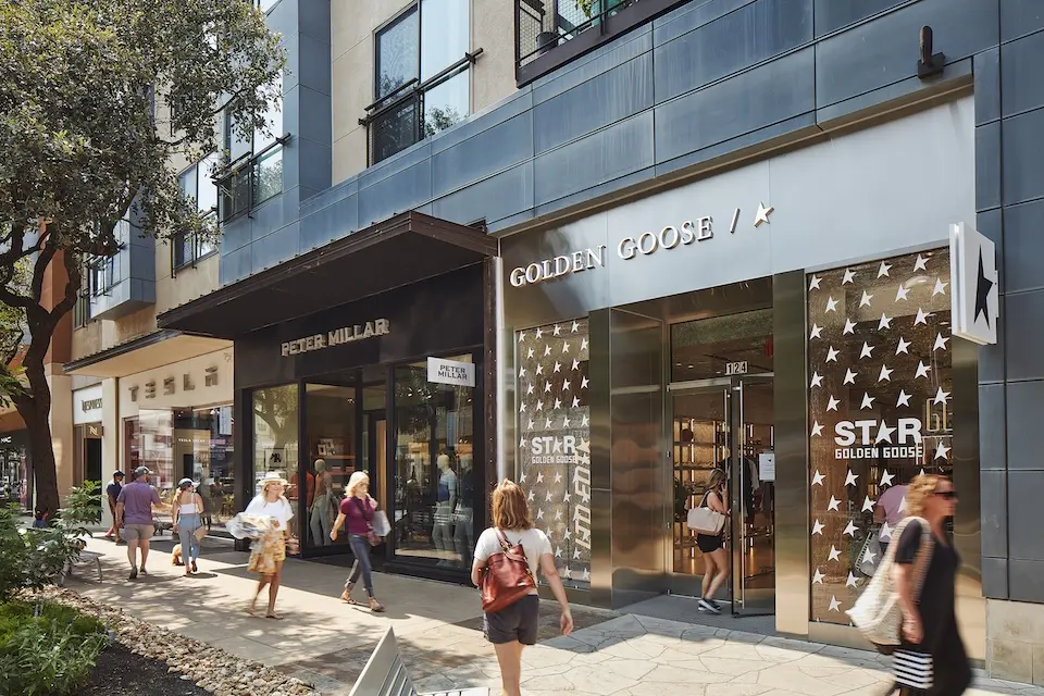 The Domain - shoppers walking past the storefronts of Golden Goose, Peter Millar and Tesla