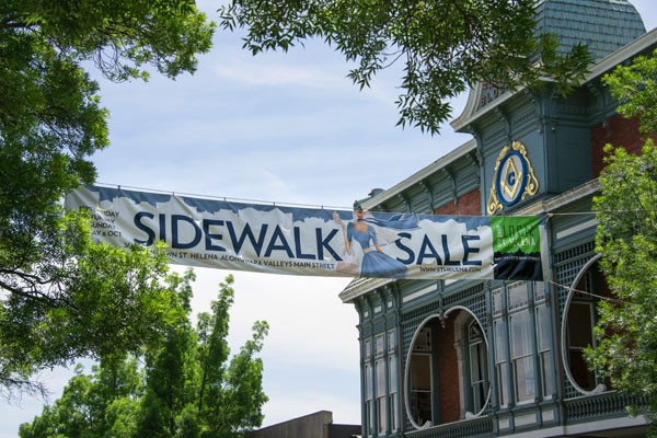 Sidewalk Sale Sign Hung up High attached to an old building and a tree