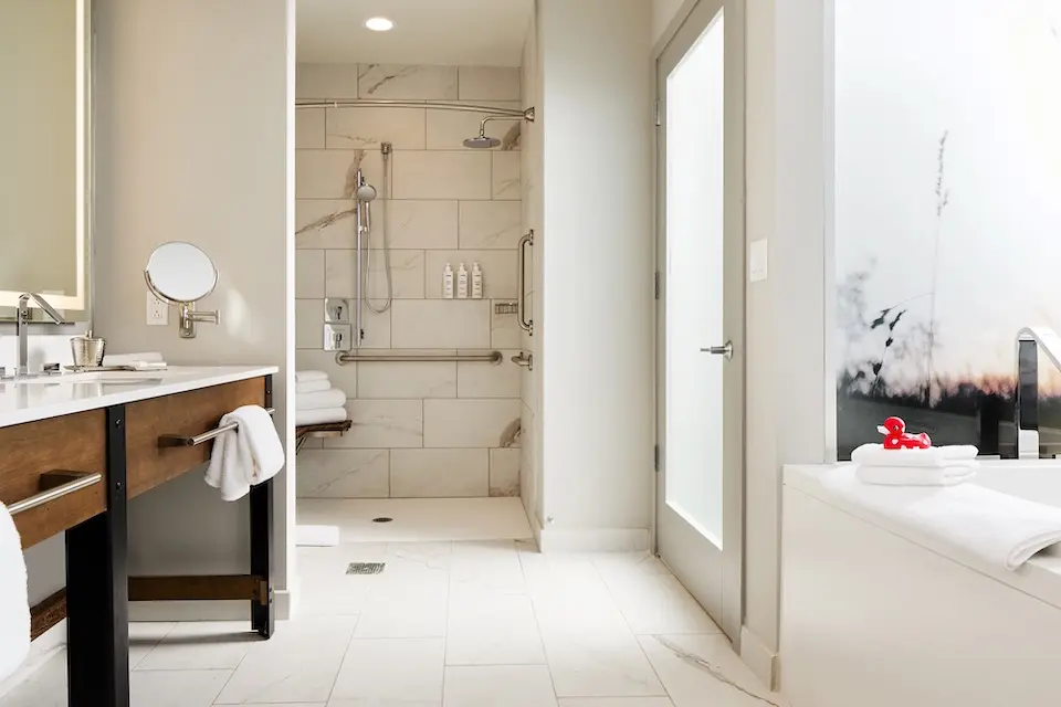 Archer's Den - spacious bathroom featuring a double vanity, mobility-accessible roll-in shower and soaking tub