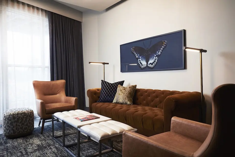 Archer's Den - living area featuring a dark caramel crushed velvet sofa and wingback chairs