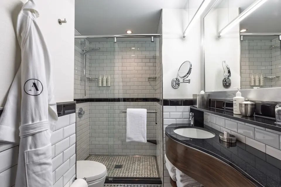Classic Queen - elegant black-and-white subway-tile bathroom with sink, shower and Frette robe hanging
