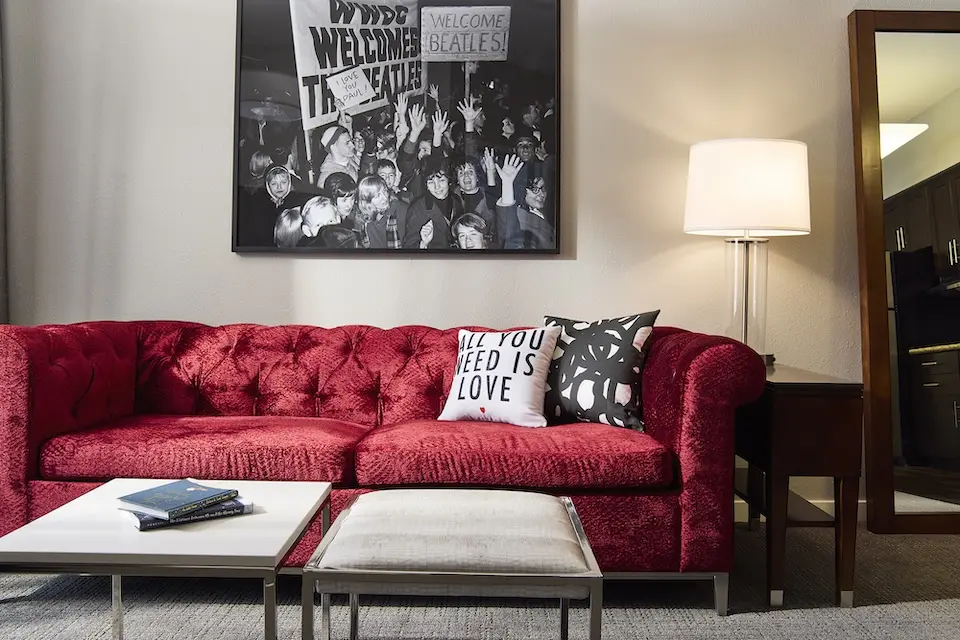 Archer's Den - a cranberry crushed velvet sleeper sofa and white quartz- and white-snakeskin coffee tables