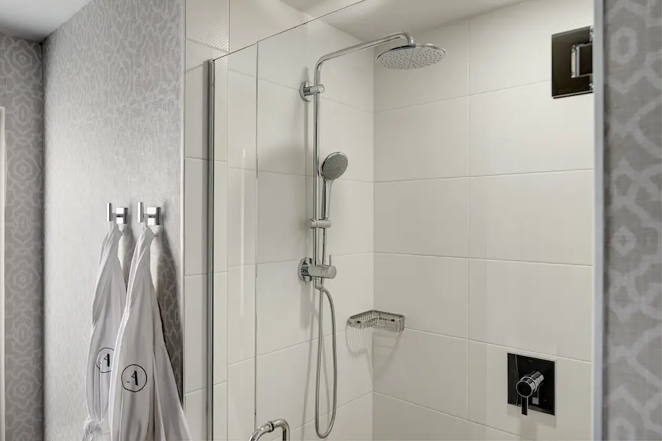 Classic King - white porcelain tiled walk-in shower with two Frette robes hanging nearby
