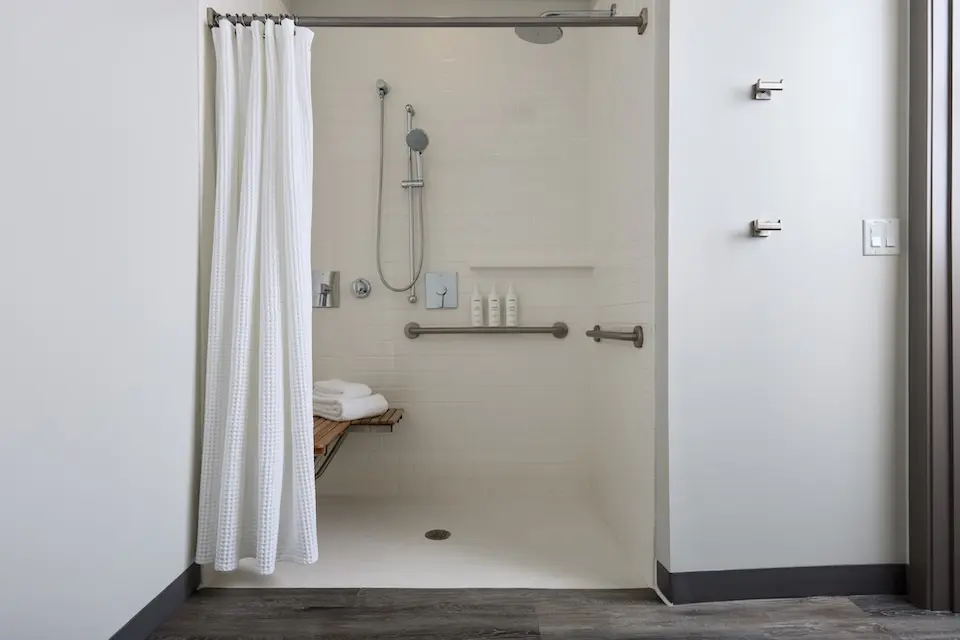Archer's Den - mobility-accessible roll-in shower with shower seat, hand-held shower wand and grab bars