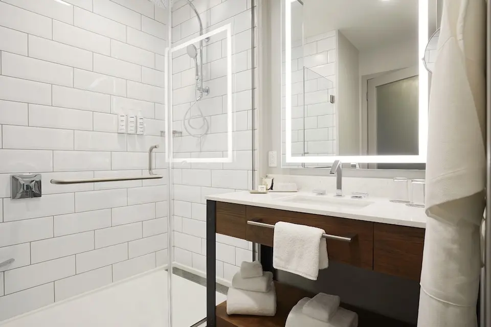 Classic King - modern bathroom with a subway-tiled walk-in shower and weathered iron vanity with lighted mirror