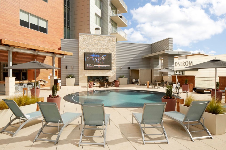 Archer Hotel Austin pool — the view on the wall with TV and the bar from behind the loungers