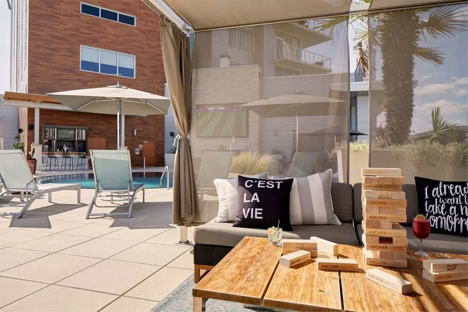 A pool cabana with soft seating and a table, overlooking the pool