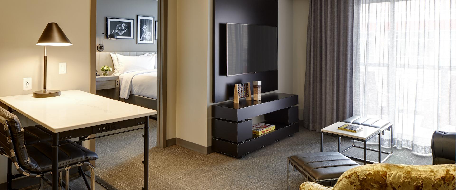 The living area in Archer's den at Archer Hotel Burlington, with a black leather sofa and gold side chair